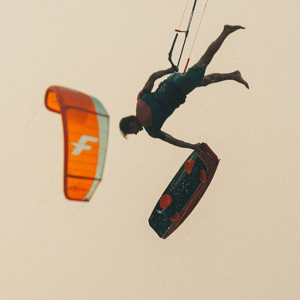 Kitesurfer performing a jump at sunset - KitesurfBase gear reviews.